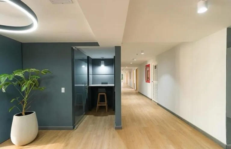 Pasillo de oficinas en la Torre Tequendama con aro LED suspendido, cabina con banco alto y downlights