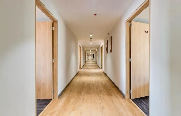 Pasillo largo de oficinas en la Torre Tequendama con downlights empotrados en el techo y piso de madera