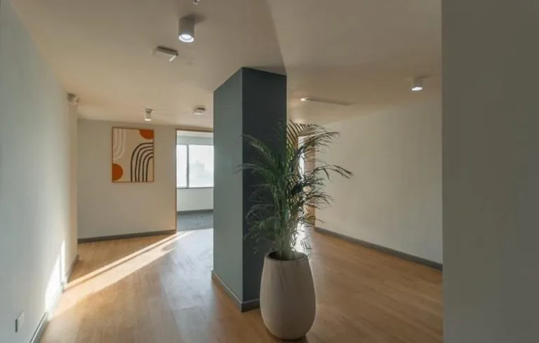 Circulación de oficinas en la Torre Tequendama con downlights, columna azul, planta y luz natural lateral