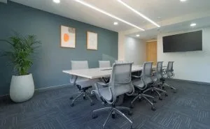 Sala de juntas en la Torre Tequendama con líneas LED empotradas en el cielorraso sobre la mesa y downlights