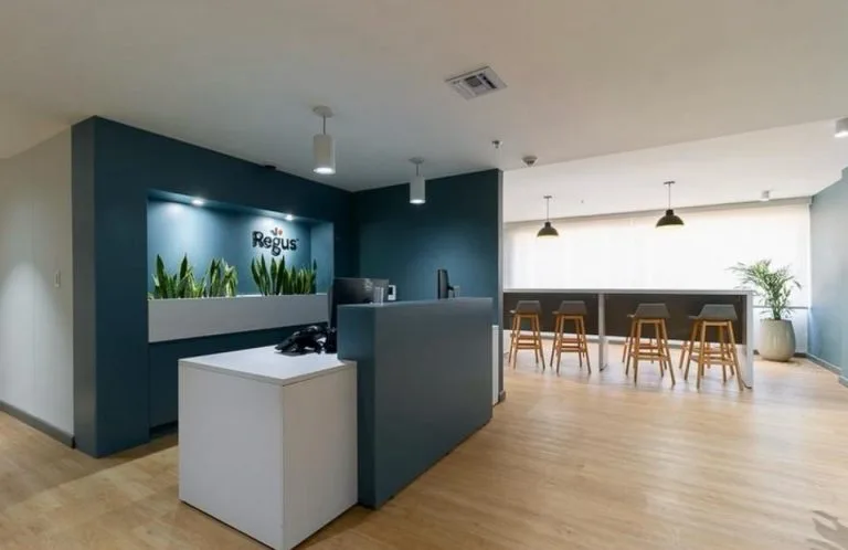 Recepción de oficinas en la Torre Tequendama con nicho de plantas iluminado, colgantes y cafetería al fondo