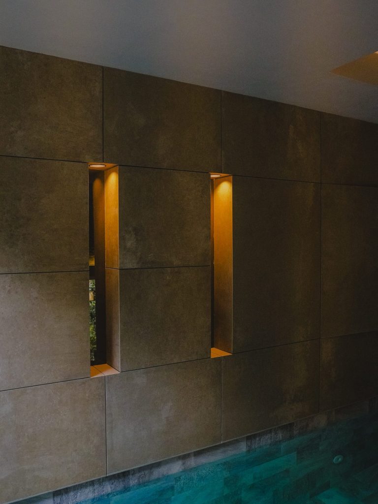 Muro de piedra con ranuras iluminadas junto a la piscina, vista lateral, Edificio Tempo